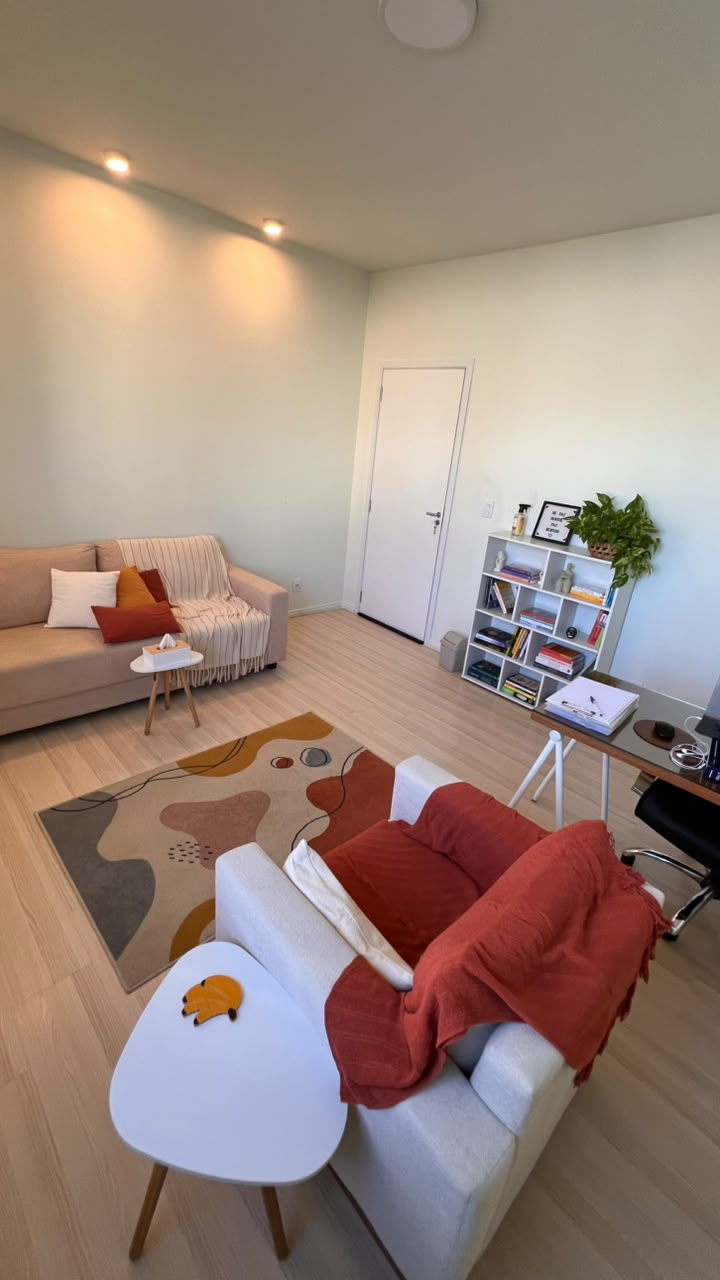 Sala de atendimento com sofá, poltrona, tapete e mesa